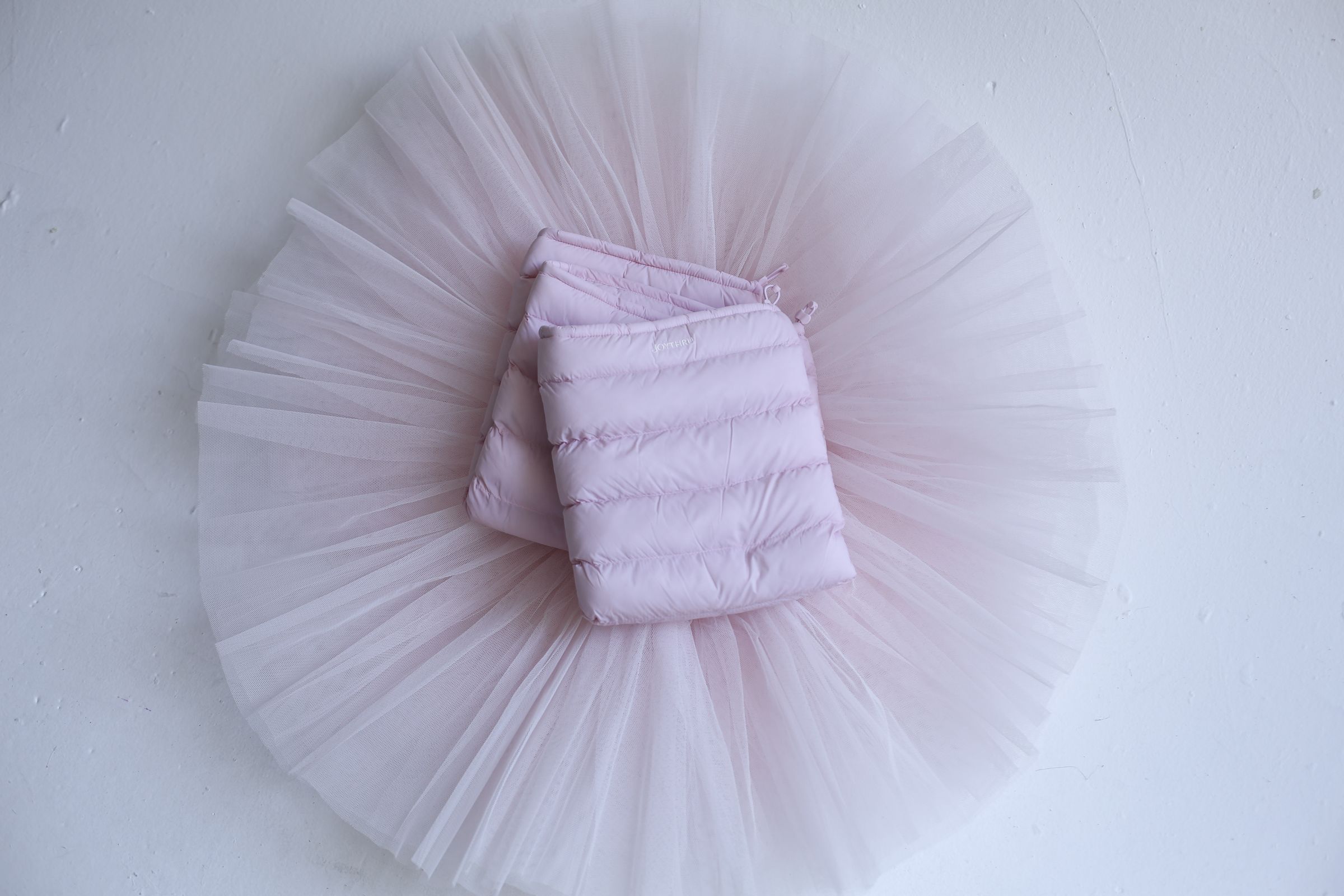 Blush LegPuffs folded on a blush tutu, flatlay on white