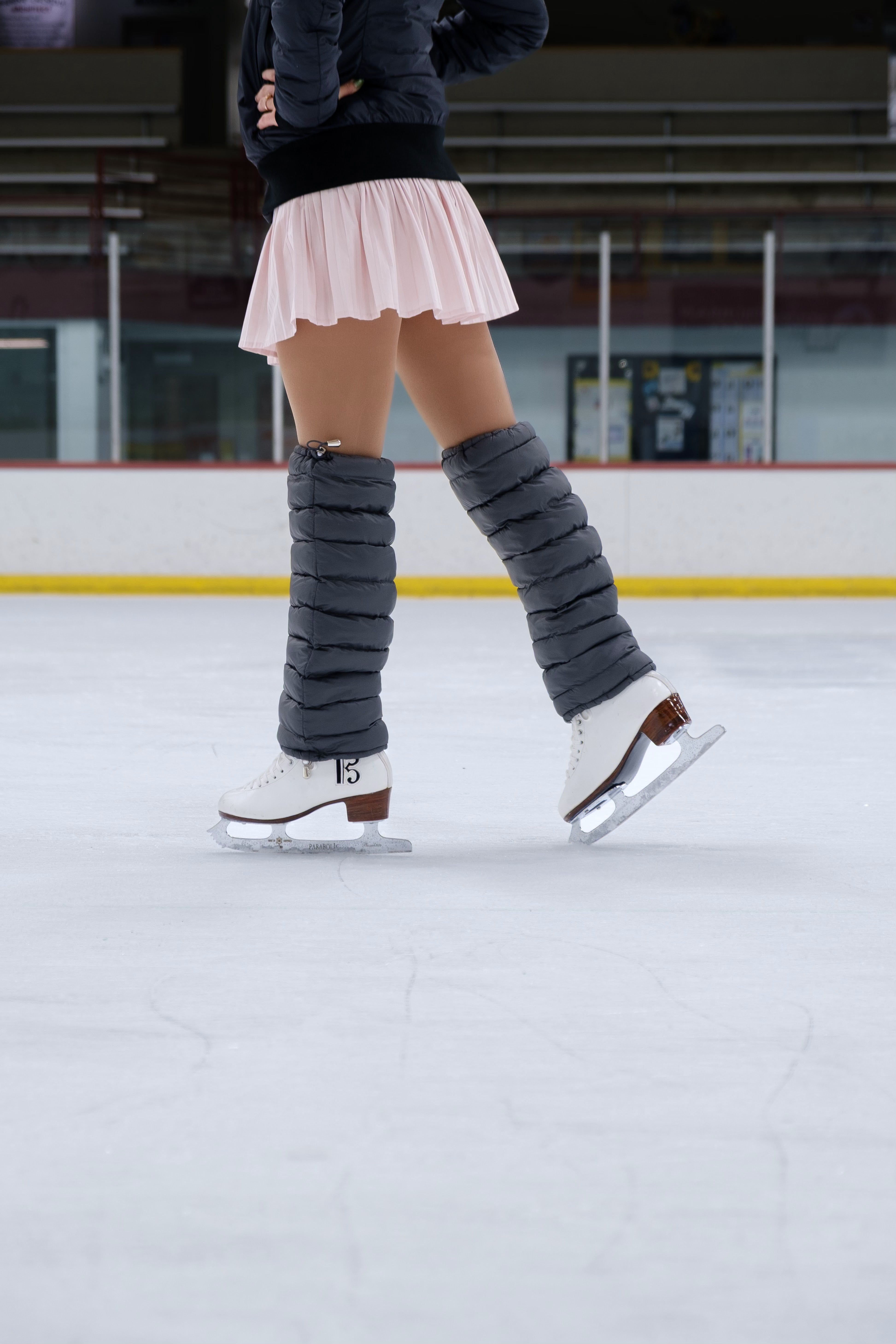 Close-up of Charcoal LegPuffs on the ice, skates apart