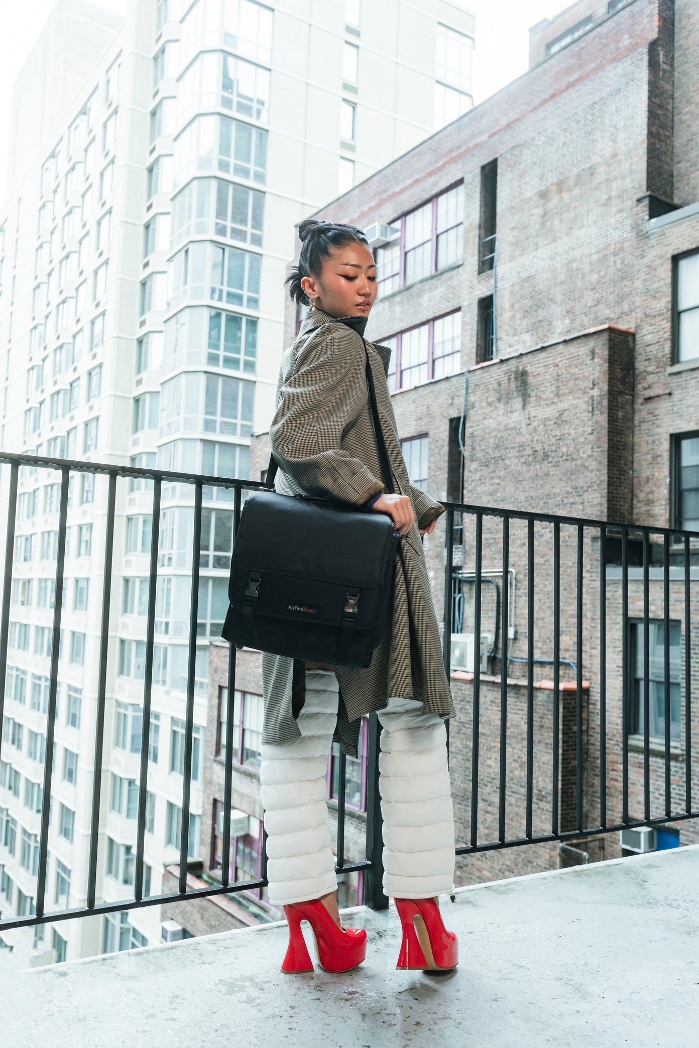 Dancer on a New York City balcony carrying the JoyThru Dance Bag, wearing white LegPuffs