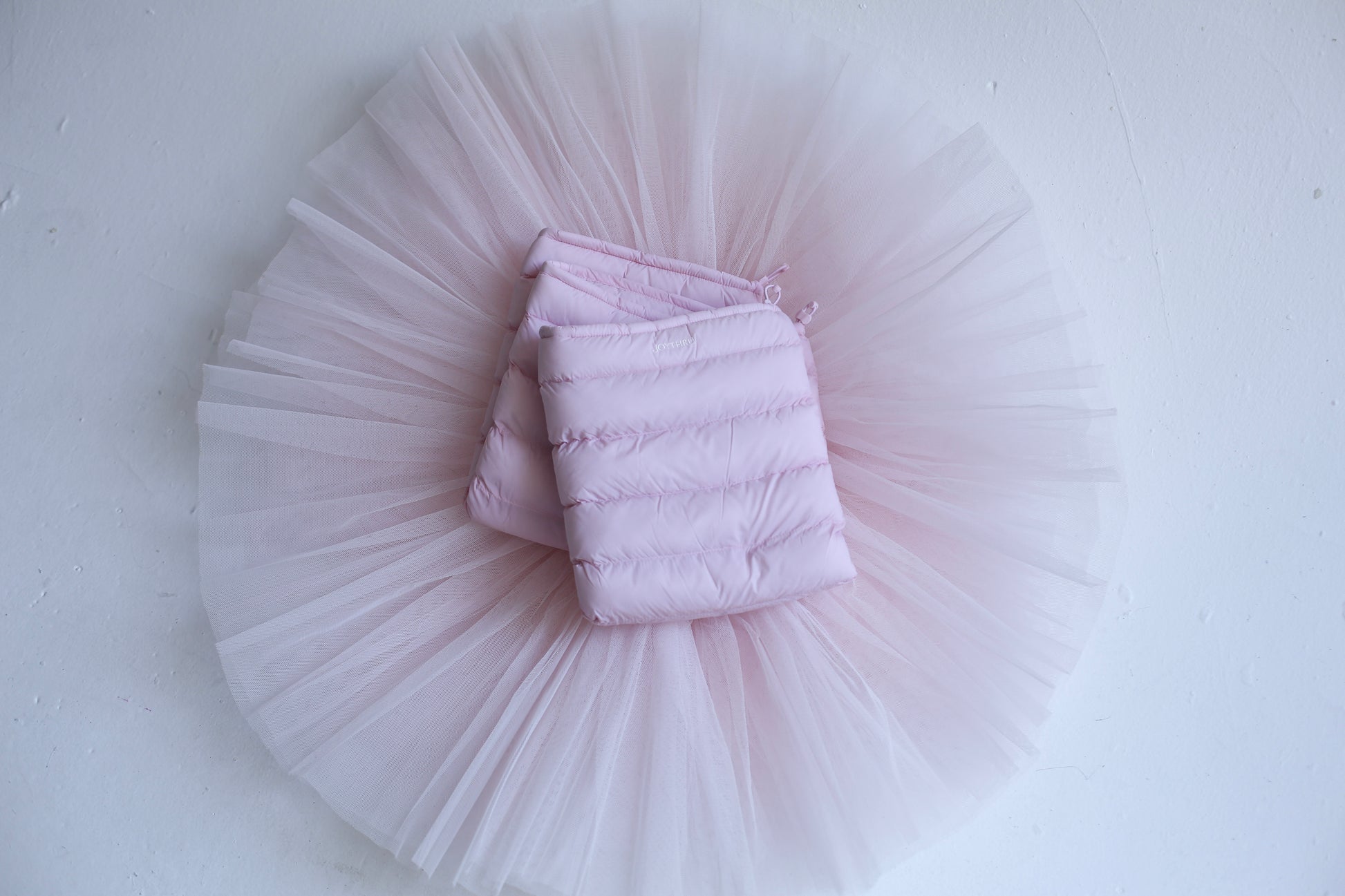 Blush LegPuffs folded on a blush tutu, flatlay on white