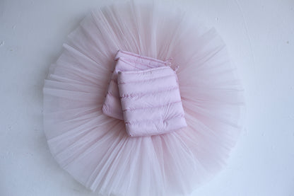 Blush LegPuffs folded on a blush tutu, flatlay on white
