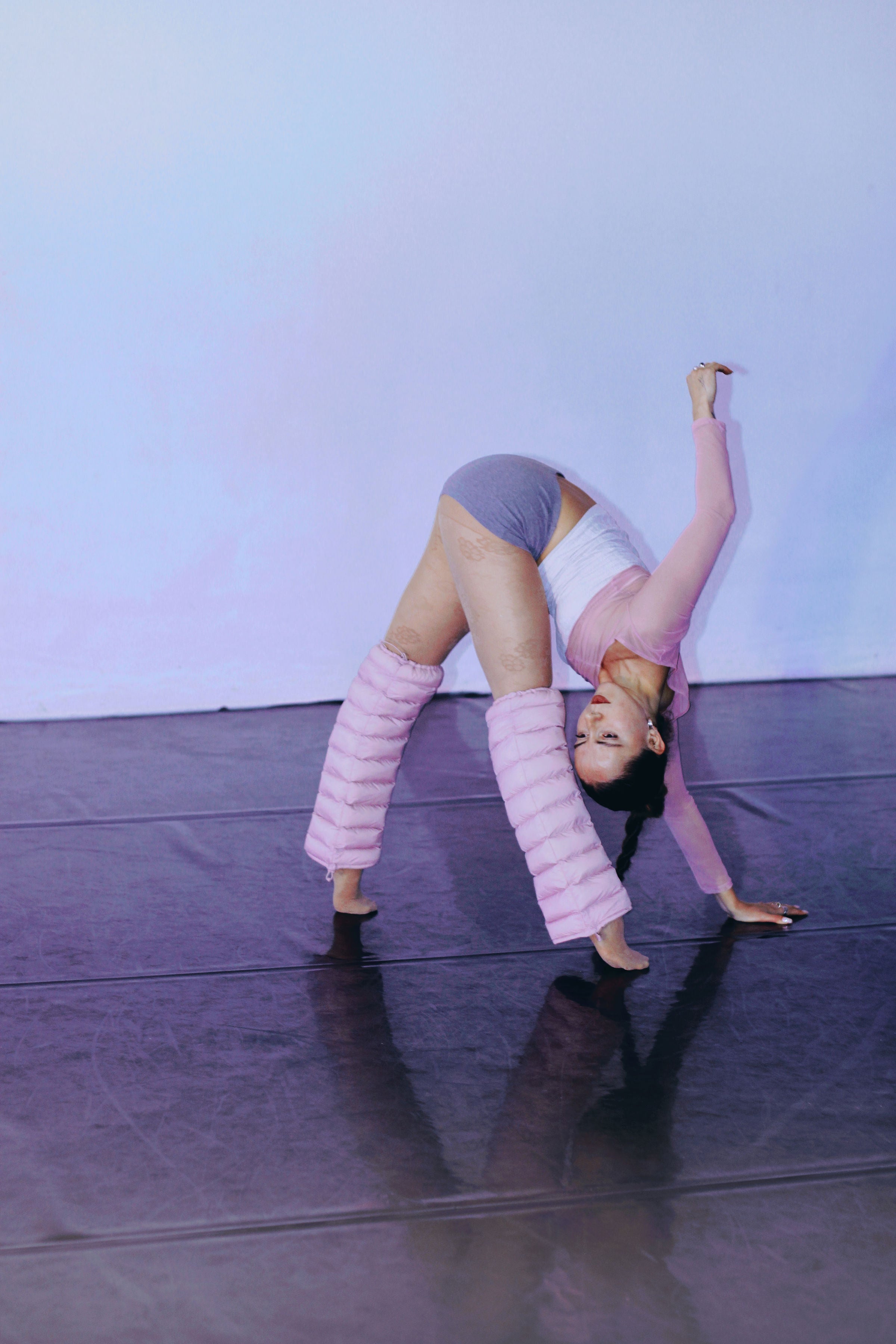 Dancer in a bridge pose wearing Blush LegPuffs on a reflective studio floor