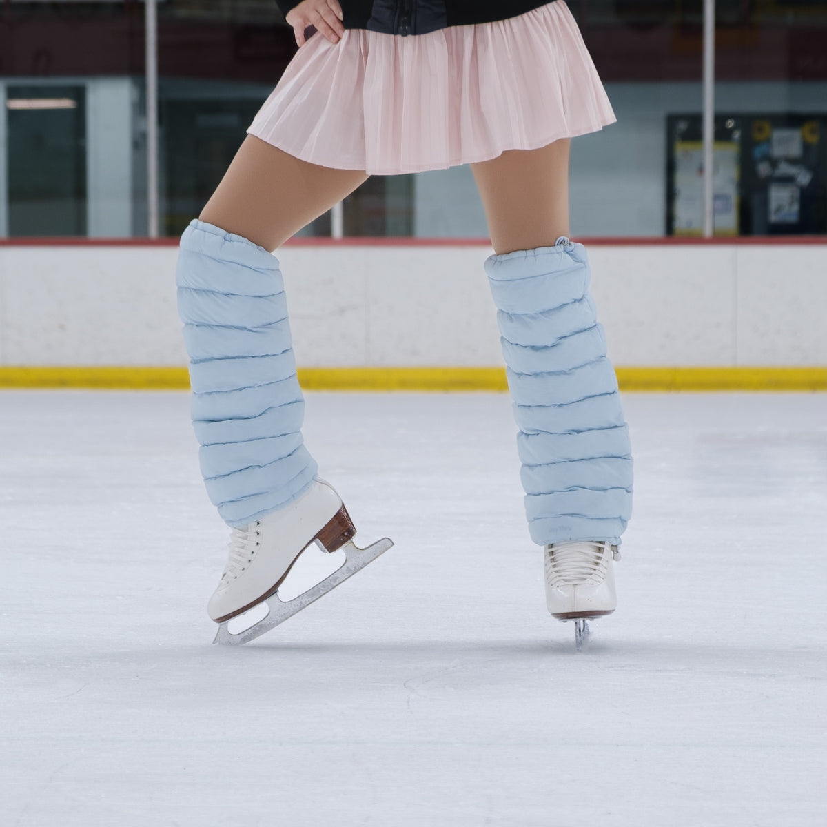 Figure skater on ice wearing Sky LegPuffs, close-up from skirt to skates
